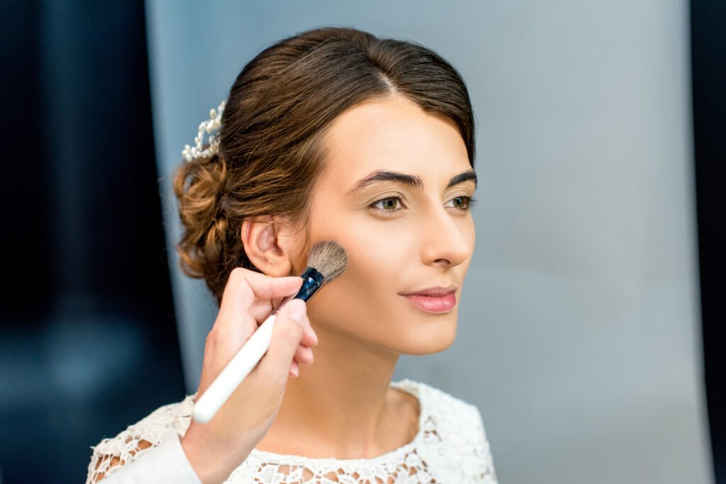 portrait of young woman getting makeup done by makeup artist